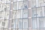 Detail of businessman and woman walking on corridor of glass fronted hotel