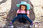 Cute girl leaning against tree trunk using digital tablet