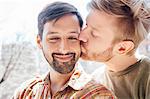 Portrait of male couple, mid adult man kissing his partner's cheek