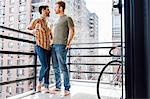 Male couple standing on balcony, face to face