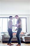 Male couple at home, dancing together, face to face