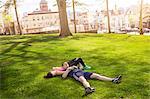 Romantic young sporty couple lying on grass in park