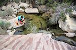 High angle view of female hiker drinking water in rock pool, Mount Wilson, Nevada, USA