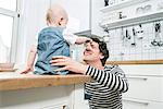 Father playing with baby boy in kitchen