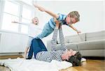 Father playing with two children in living room