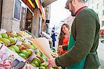 Grocer and customer looking at fruit variety