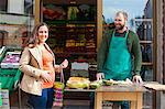 Customer and grocer in front of greengrocer's shop