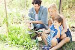 Parents teaching little boy how to garden