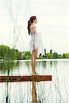 Woman standing at end of lake pier, looking at view