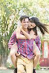 Couple together outdoors, man giving woman a piggyback ride