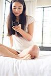 Woman sitting in bed using smartphone