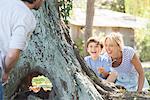 Young boy and mother hiding behind tree, playing hide-and-seek