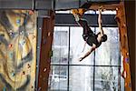 Young man practicing rock-climbing on a rock wall indoors