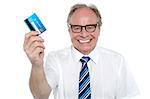 Cheerful aged employer holding up a cash card and smiling at the camera.