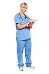 Full length portrait of a smiling nurse preparing case sheet of a patient.