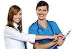 Attractive girl pointing at the doctors case sheet. Nurse and girl both facing camera.