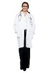 Full length portrait of a cheerful female doctor with hands in lab coat pocket.