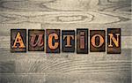 The word "AUCTION" theme written in vintage, ink stained, wooden letterpress type on a wood grained background.