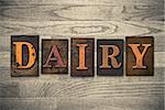 The word "DAIRY" theme written in vintage, ink stained, wooden letterpress type on a wood grained background.