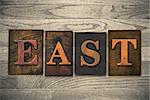 The word "EAST" theme written in vintage, ink stained, wooden letterpress type on a wood grained background.