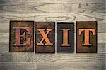 The word "EXIT" theme written in vintage, ink stained, wooden letterpress type on a wood grained background.