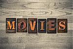 The word "MOVIES" theme written in vintage, ink stained, wooden letterpress type on a wood grained background.