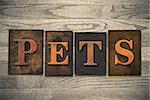 The word "PETS" theme written in vintage, ink stained, wooden letterpress type on a wood grained background.