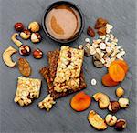 Arrangement of Useful Granola Bars with Muesli, Nuts, Seed, Raisins, Dried Apricots and Bowl of Honey closeup on Black Stone background