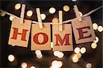 The word HOME spelled out on clothespin clipped cards in front of glowing lights.