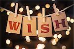 The word WISH printed on clothespin clipped cards in front of defocused glowing lights.