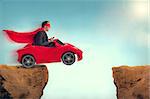 man in a red car jumping a ravine