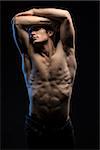 Portrait of handsome red-haired athlete topless at the studio on a black background in low key