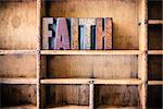 The word FAITH written in vintage wooden letterpress type in a wooden type drawer.