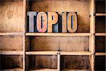 The word TOP 10 written in vintage wooden letterpress type in a wooden type drawer.