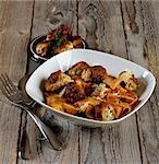 Delicious Homemade Pasta Tagliatelle with Herbs and Tomato Sauce and Beef Meatballs in White Bowl closeup on Rustic Wooden background