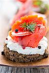 Sandwich with salted red salmon on a wooden tray.