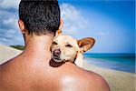 dog and owner sitting close together at the beach on summer vacation holidays, embracing a hug