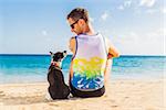 dog and owner sitting close together at the beach on summer vacation holidays
