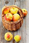 Fresh Ripe Apricots in Wicker Basket closeup on Rustic Wooden background