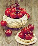 Two Wicker Bowls with Ripe Sweet Cherries isolated on Rustic Wooden background. Retro Styled