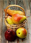 Arrangement of Yellow, Red and Conference Pears in Wicker Basket closeup on Rustic Wooden background