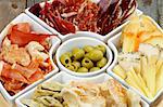 Serving Plate with Various Spanish Cheeses, Jamon, Cured Ham, Green Olives and Bread Sticks closeup on Wooden background