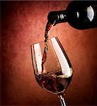 Wine pouring in wineglass on a brown background
