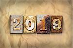 The word "2019" written in rusty metal letterpress type on a crumbled aged paper background.