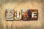 The word "BIKE" written in rusty metal letterpress type on a crumbled aged paper background.