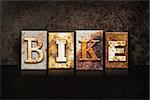 The word "BIKE" written in rusty metal letterpress type on a dark textured grunge background.