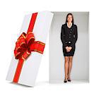 Businesswoman looking at camera in gift box with ribbon on isolated white background