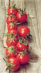 Ripe Cherry Tomatoes with Stems In a Row on Rustic Wooden background. Focus on Foreground. Retro Styled