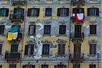 Laundry hanging from balconies on damaged facade of building with windows, Turin, Italy