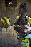 Mother holding child in arms while nursing, black and yellow patterns, Gaoua, Poni Province, Burkina Faso